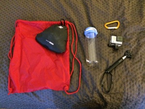 a red bag with a water bottle and a camera on a brown surface