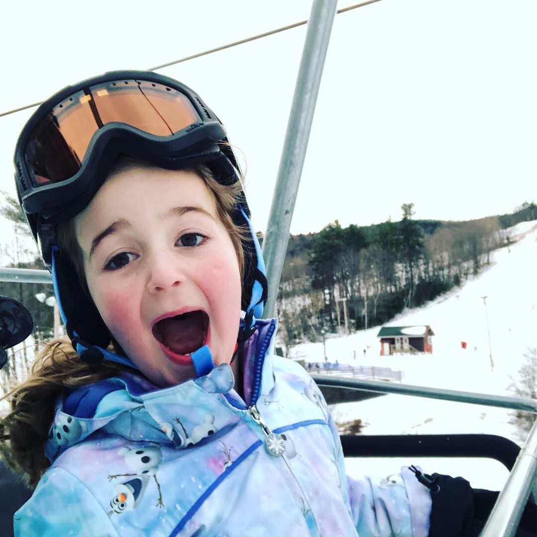 a child wearing ski goggles and a blue jacket