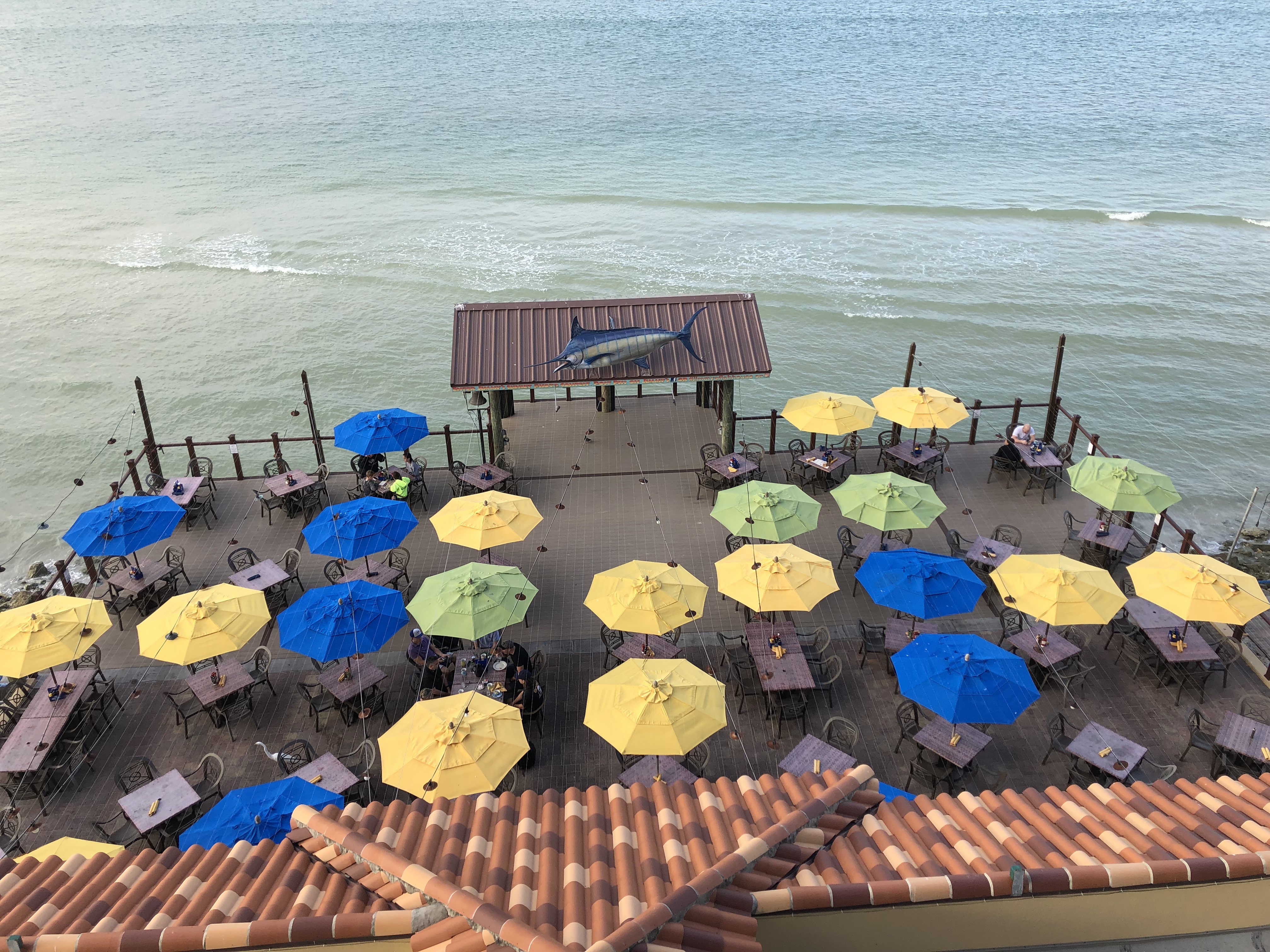 a group of umbrellas and tables on a dock by the water