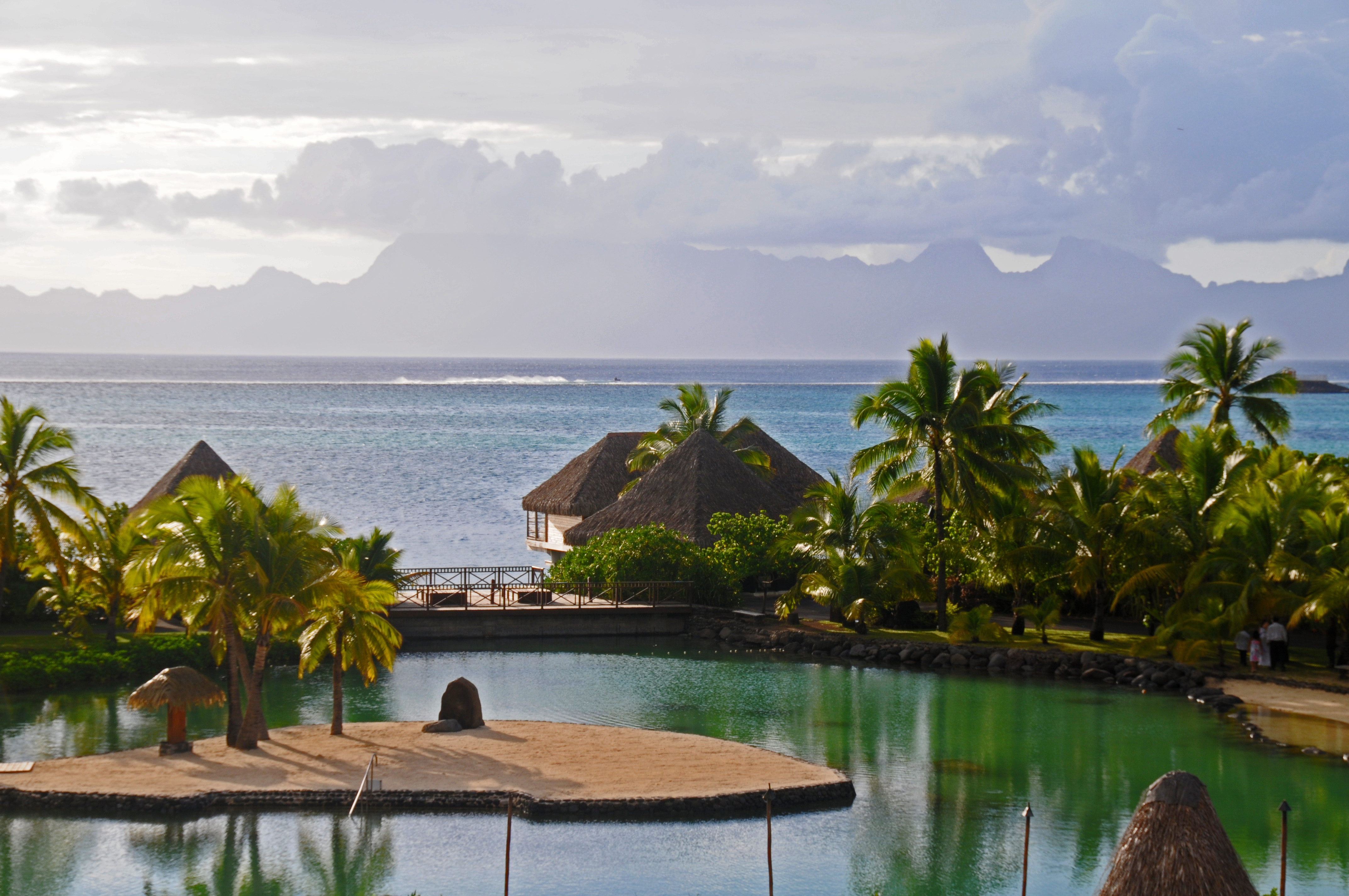 a body of water with a hut and palm trees