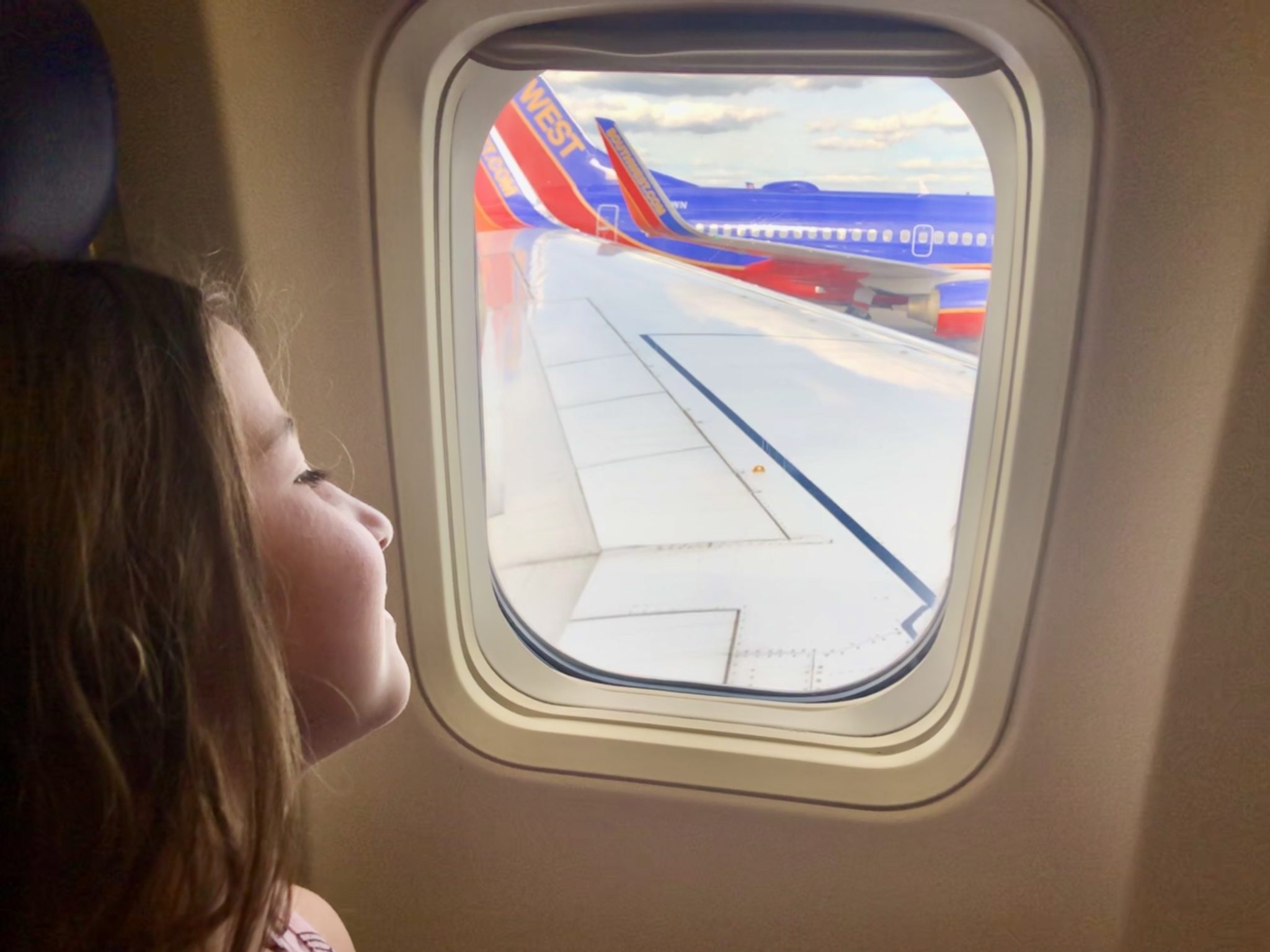 a girl looking out a window at an airplane